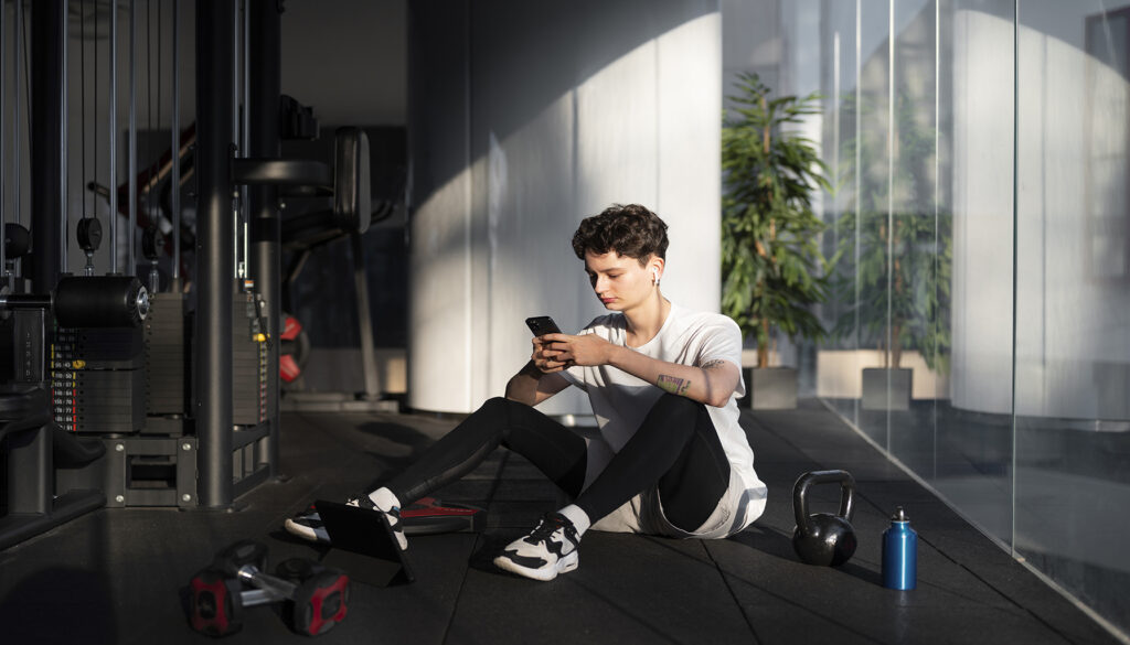 An individual takes a pre-workout drink before starting their workout routine in a gym.